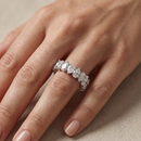 Diamond ring on a person's finger against a neutral background